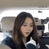 a young woman is giving a thumbs up while sitting in the back seat of a car .