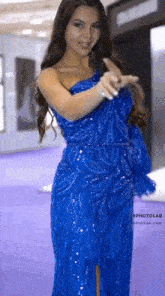 a woman in a blue dress is dancing on a purple carpet .