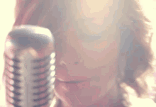 a close up of a woman singing into a microphone with her eyes closed