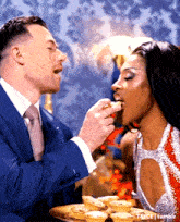 a man in a suit and tie feeding a woman a piece of food