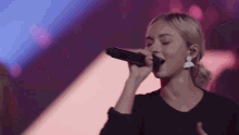 a woman is singing into a microphone on a stage .