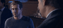 a man in a grey shirt is talking to another man