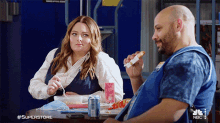a man and a woman are sitting at a table with #superstore written in the corner