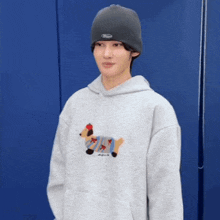 a young man wearing a beanie and a hoodie with a dog on it .