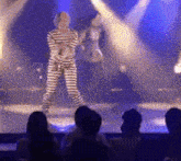 a man in a striped prison uniform sings into a microphone