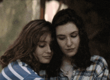 two women are hugging each other with one wearing a plaid shirt with the letter c on it