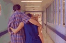 a man and a woman are walking down a hallway with their arms around each other