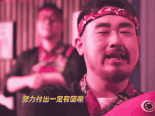 a man with a beard wearing a headband and a pink shirt