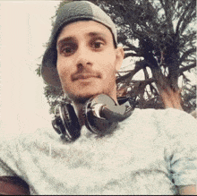 a man wearing headphones and a hat is taking a picture of himself .