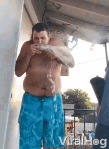 a shirtless man in blue shorts is drinking water from a bottle ..