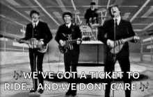 a black and white photo of the beatles playing guitars and singing on a stage .