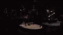 a group of people are dancing on a stage in a dark room while holding a tambourine .