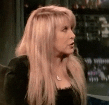 a woman with long blonde hair is wearing a black shirt and necklace