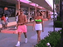 a man and woman are walking down a sidewalk .
