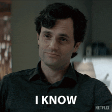 a man in a grey shirt says i know in white letters