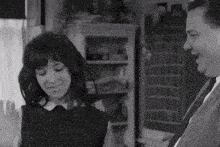 a black and white photo of a man and a woman standing next to each other .