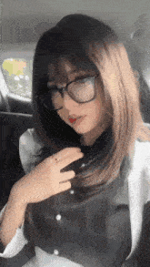 a woman wearing glasses is sitting in a car .