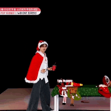 a young man is wearing a santa hat and cape while holding a cup .