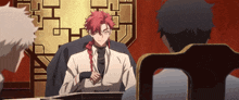 a man with red hair sits at a table with two other men