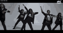 a group of women in suits and ties are dancing in front of a sign that says the k