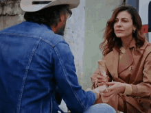 a man in a cowboy hat holds the hand of a woman