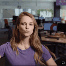 a woman wearing a purple shirt is making a funny face