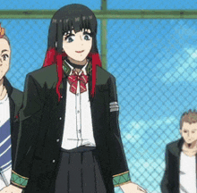 a girl with red hair is standing in front of a chain link fence with other people .