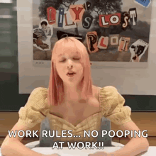 a woman with pink hair is sitting at a desk in front of a poster that says work rules no pooping at work .