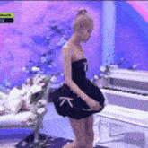 a woman in a black dress is standing next to a piano .