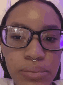 a woman wearing glasses and a nose ring is looking at the camera