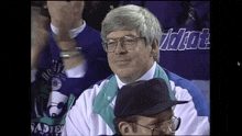 a man wearing glasses is sitting in a crowd wearing a shirt that says wildcat