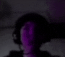 a blurry picture of a person wearing headphones with purple lights behind them .