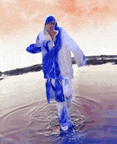 a painting of a person in a blue and white outfit standing in a body of water
