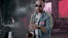a man is playing a saxophone on a stage while wearing sunglasses .