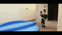 a man is carrying a child in his arms in front of a large inflatable pool