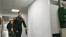 a man walking down a hallway with a bag and a sign that says emergency exit