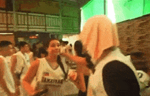 a group of people are standing in a room and one of them is wearing a jersey that says akita .