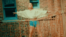 a woman is standing on a balcony with her arms outstretched