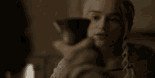 a woman is holding a wine glass in her hand and looking at the camera .