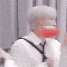 a man wearing a white shirt and tie is holding a red balloon in his mouth .