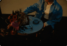 a man is sitting at a table with flowers on it .