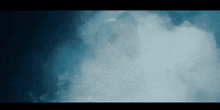a person standing in a cloud of smoke with a blue sky in the background