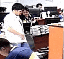 a group of people are sitting at desks in an office with computers .