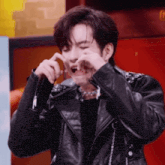 a man wearing a black leather jacket is making a face
