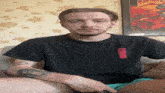 a man sitting on a couch with a black shirt that has the word ninja on it