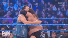 two men are hugging in a wrestling ring and the fox logo is visible in the background