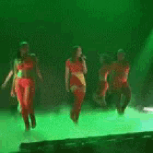 a woman in a red dress is singing into a microphone while dancing on a green stage .