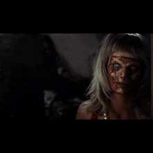 a woman with blood on her face looks at herself in a mirror