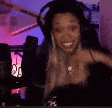 a woman wearing headphones is sitting in front of a microphone making a surprised face .