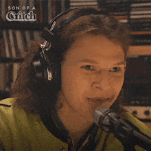 a woman wearing headphones is sitting in front of a microphone with the words son of a glitch behind her